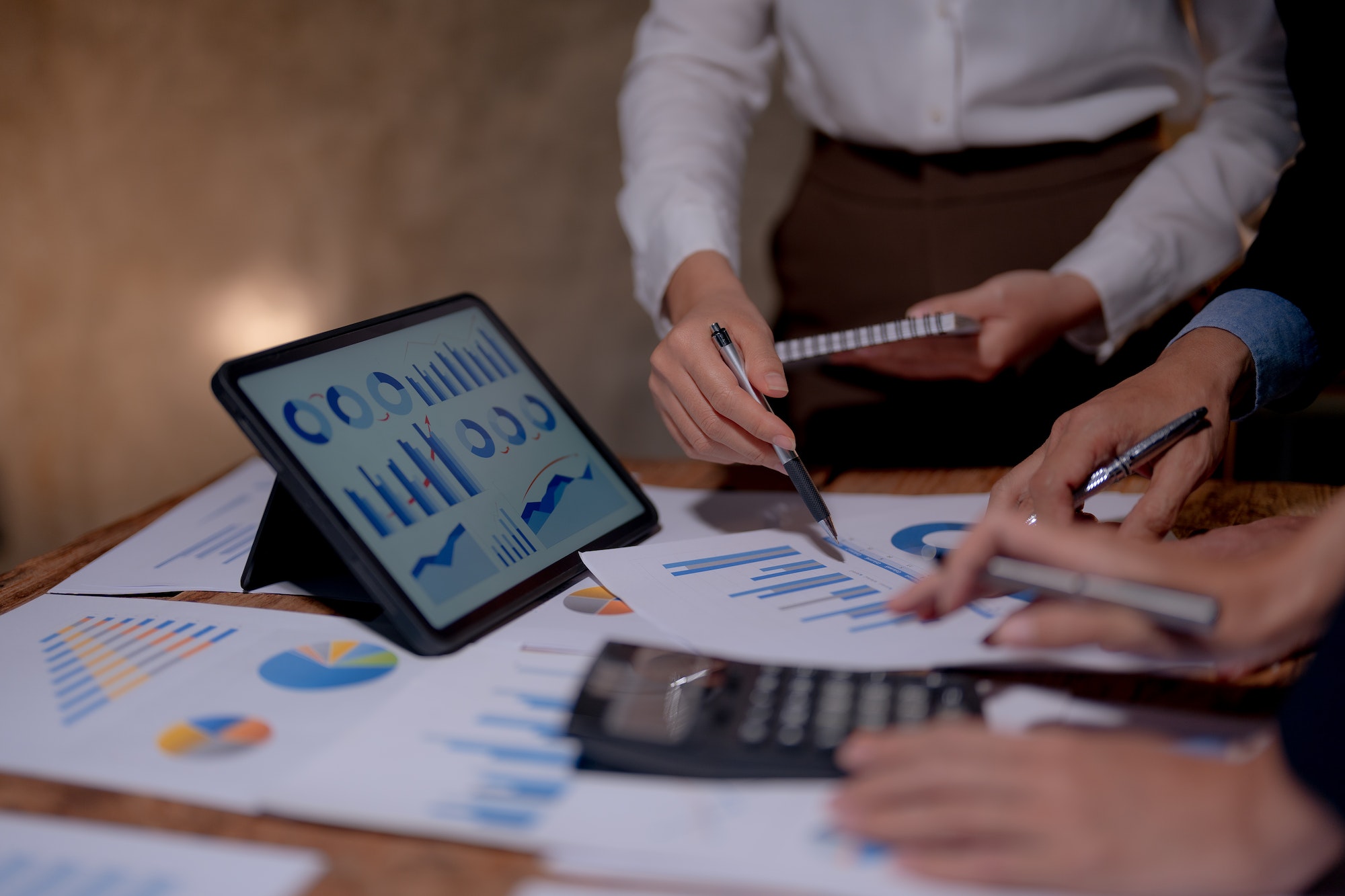 Meeting of business people pointing at graphs and charts to analyze market data, balance sheet